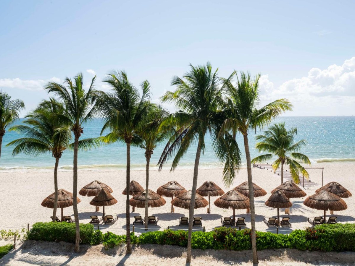 Palapa umbrellas and palms on the white-sand beach at Hyatt Zilara Riviera Maya