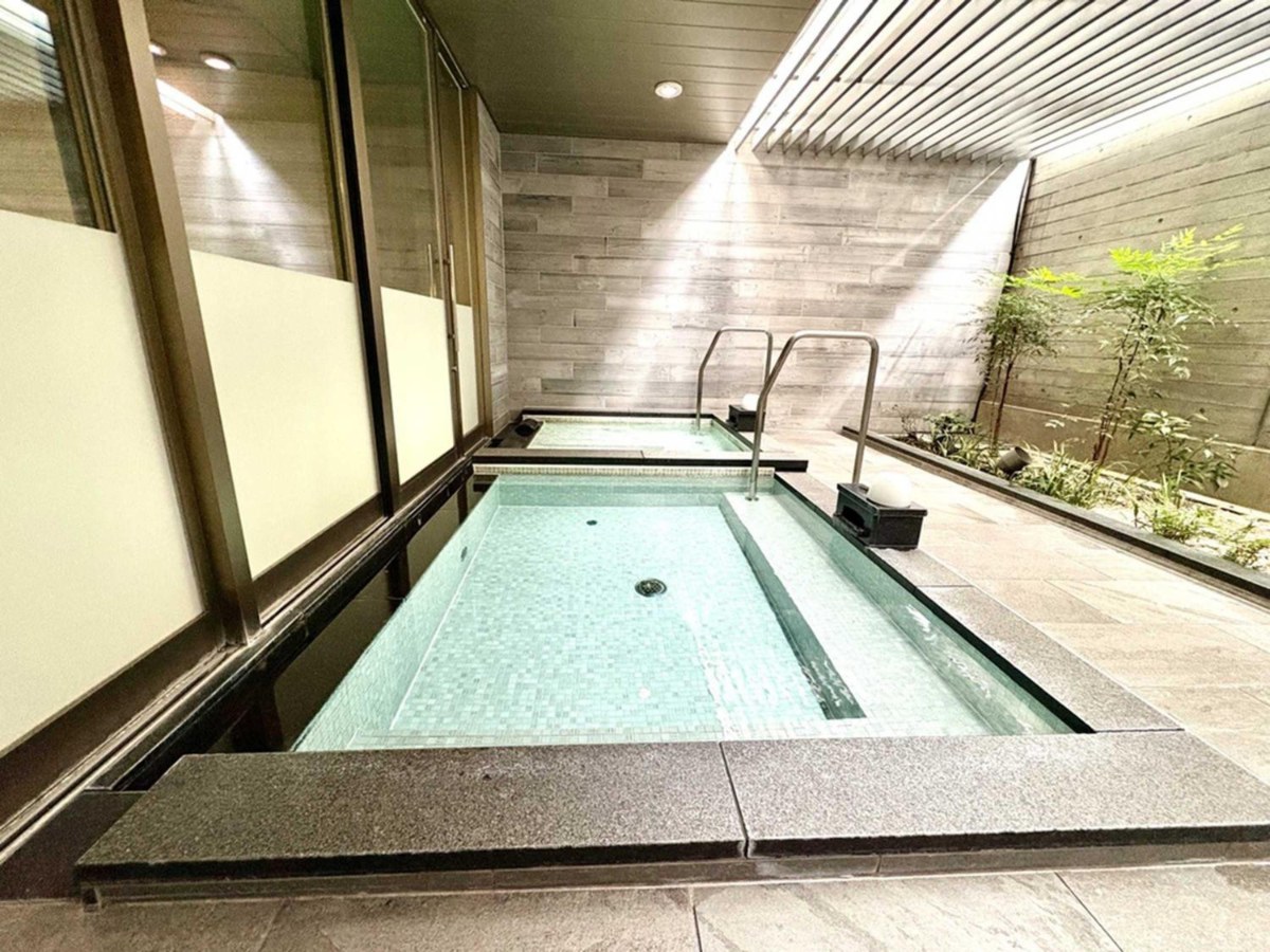 Long open-air bath under a louvred roof with planters at Nishitetsu Hotel Croom Nagoya