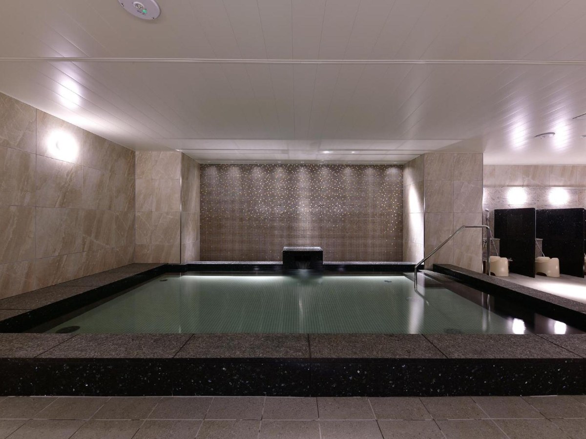 Large indoor public bath with a stone spout at Vessel Hotel Campana Nagoya