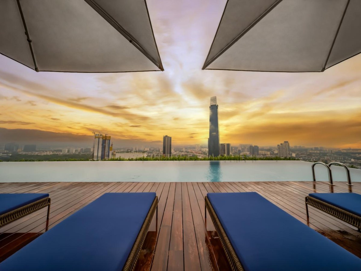 Pool loungers at sunset with a tall tower on the skyline at Capri by Fraser Bukit Bintang