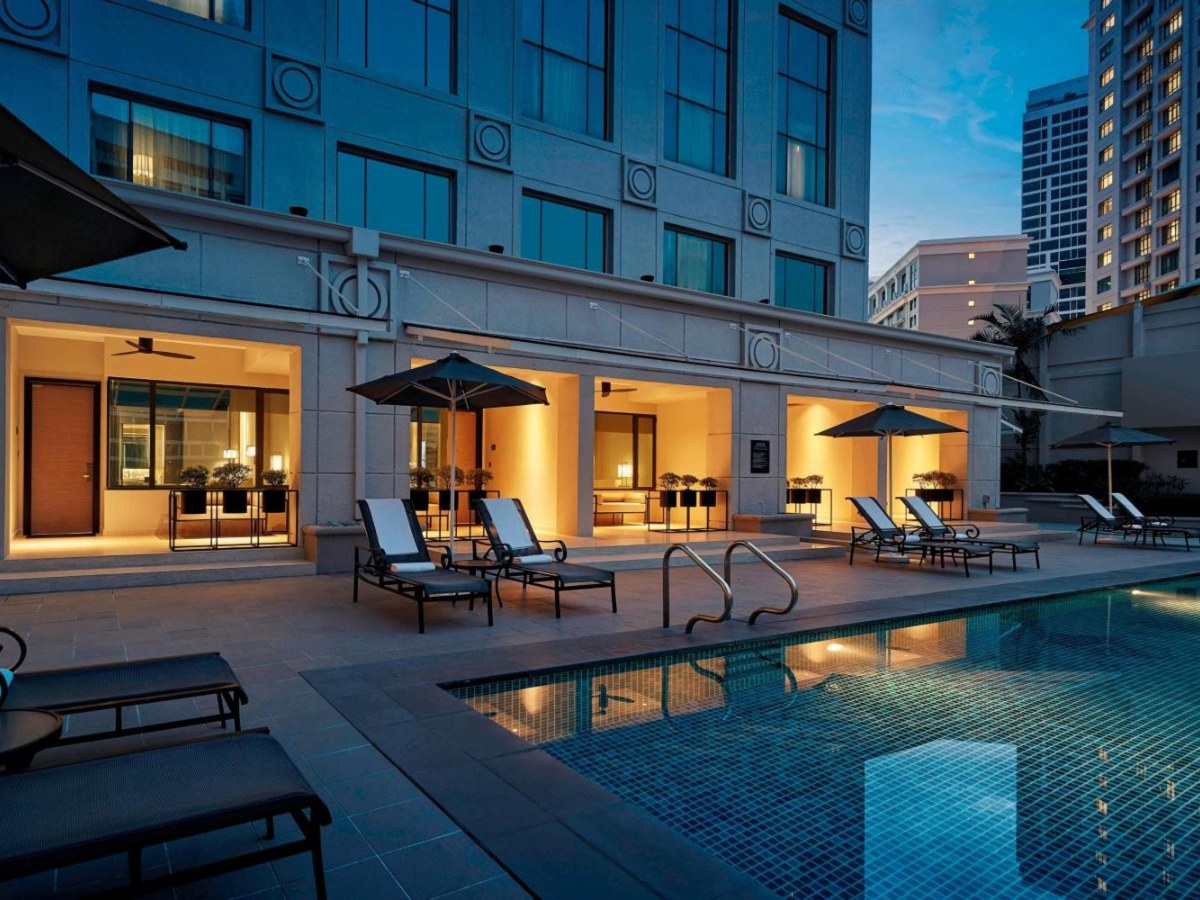 Pool with loungers and umbrellas beside the poolside rooms at JW Marriott Kuala Lumpur