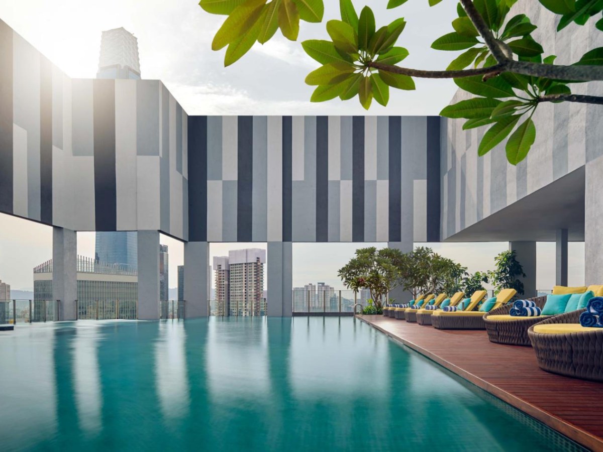 Rooftop pool with loungers and city towers behind it at Pan Pacific Serviced Suites