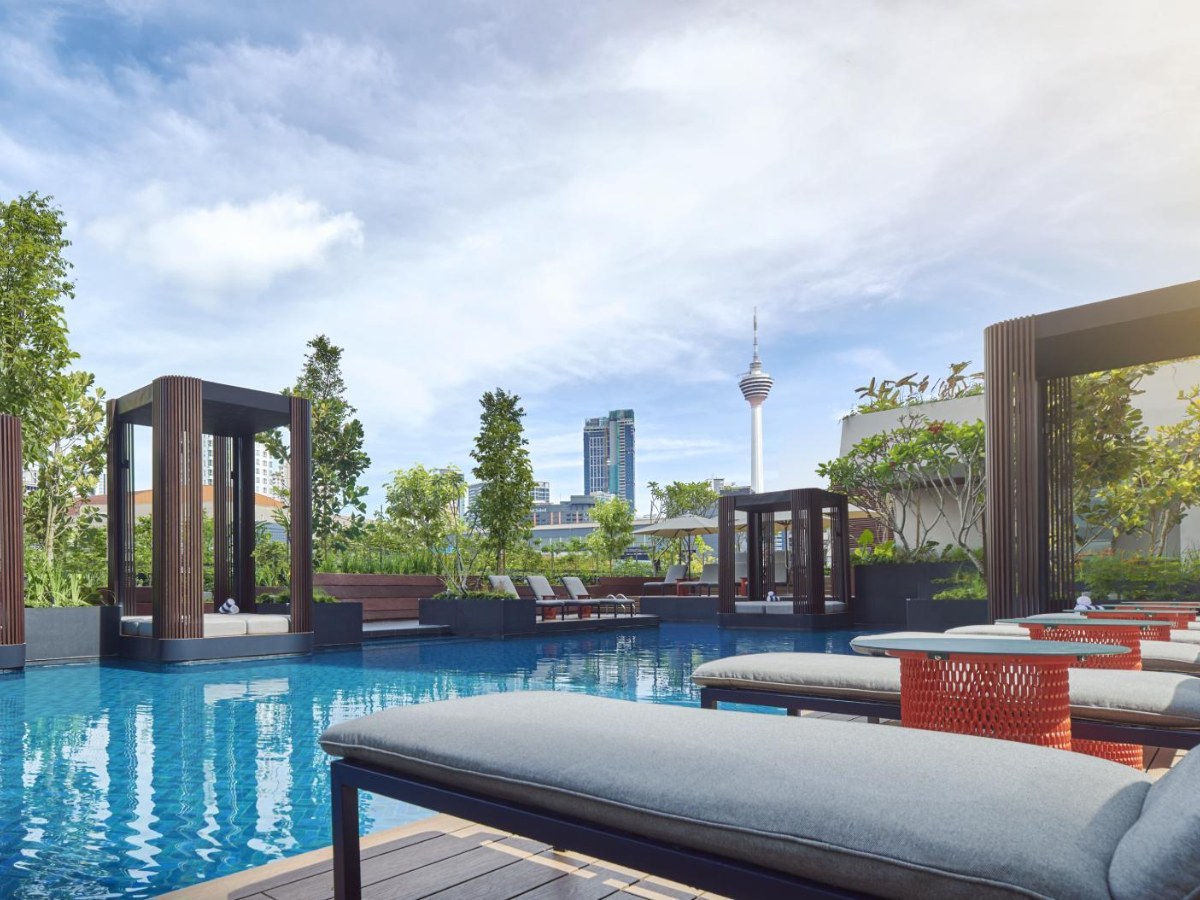 Pool deck with daybeds and KL Tower in the distance at PARKROYAL COLLECTION Kuala Lumpur