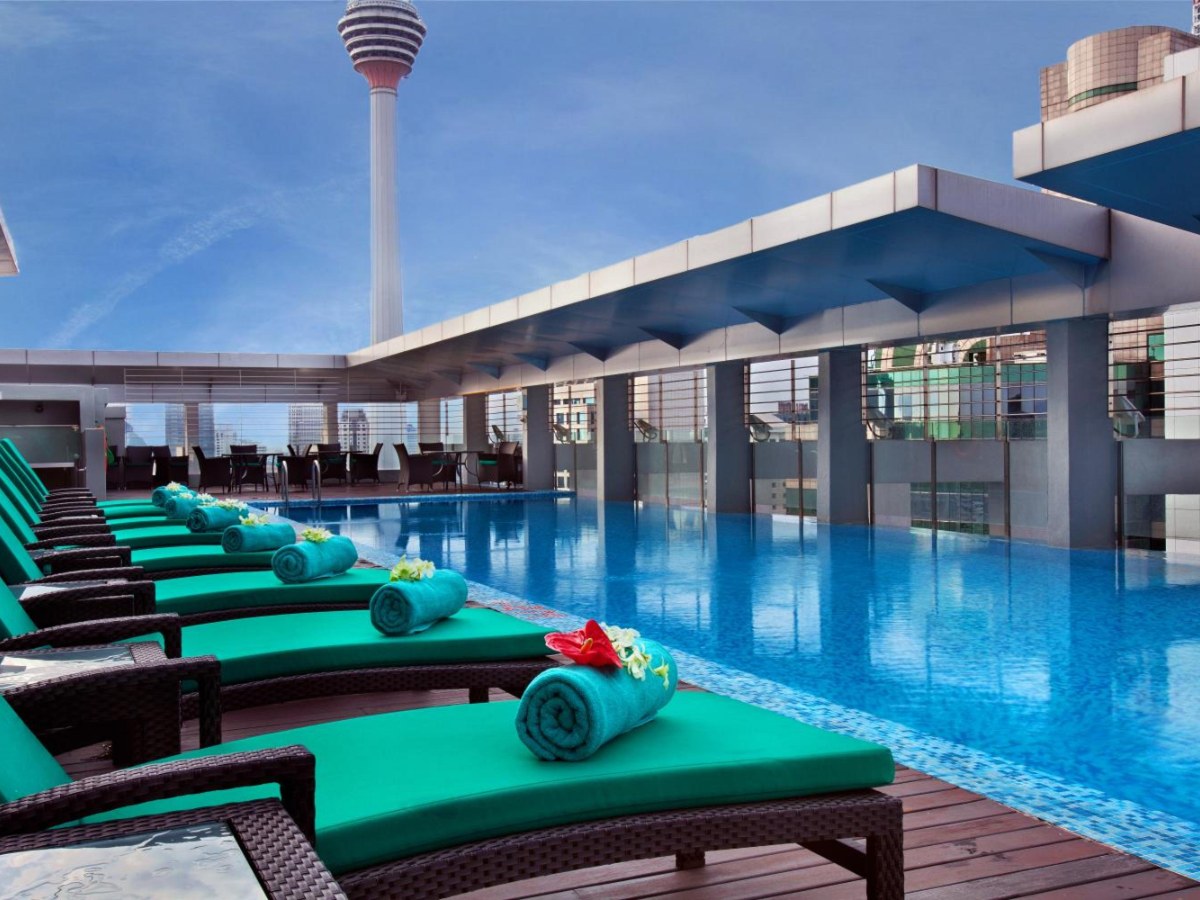 Rooftop pool with green loungers and KL Tower at PARKROYAL Serviced Suites