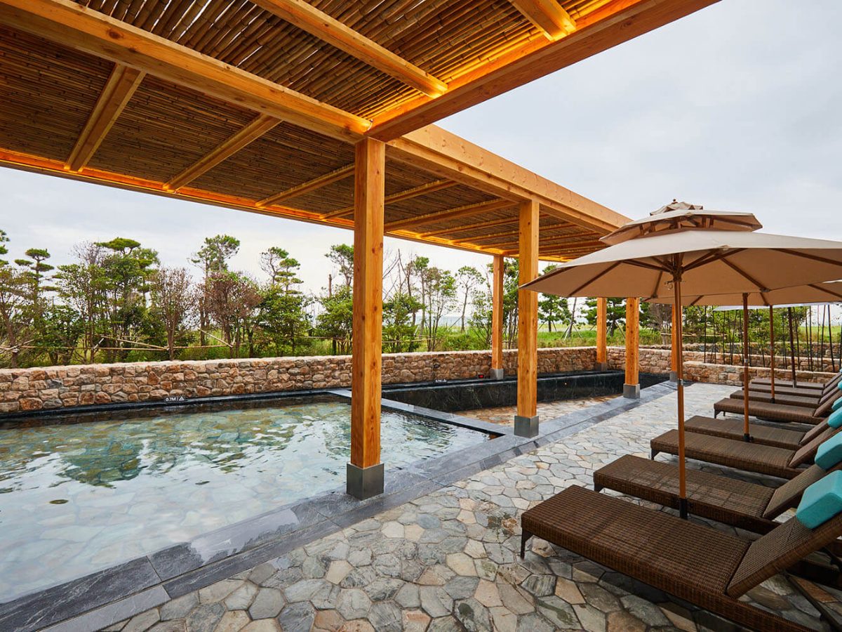 Stone-edged outdoor bath with loungers at the Water House of Ananti at Busan Cove