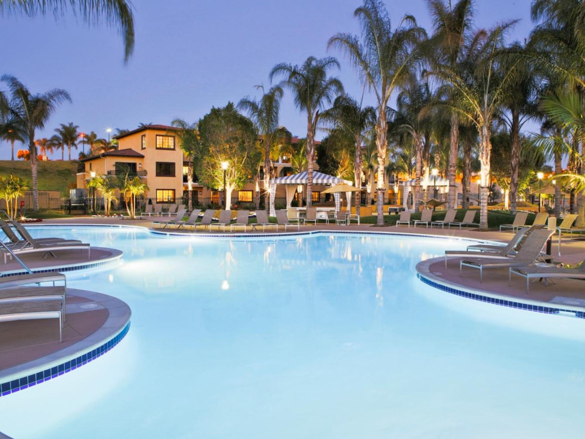 Lagoon-style pool lit at dusk among palm trees at MarBrisa in Carlsbad