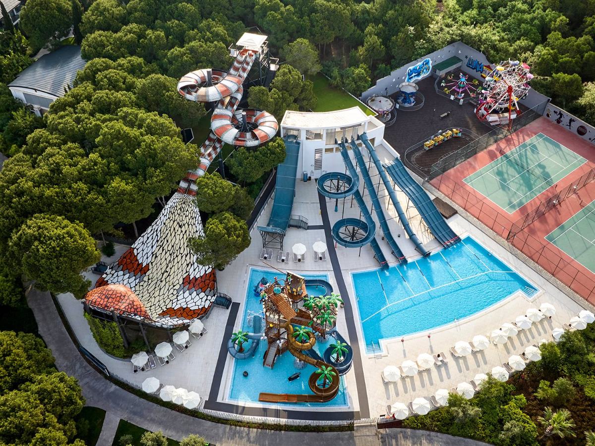 Aerial view of the aquapark slide tower and slide pool among pines at Voyage Belek Golf & Spa