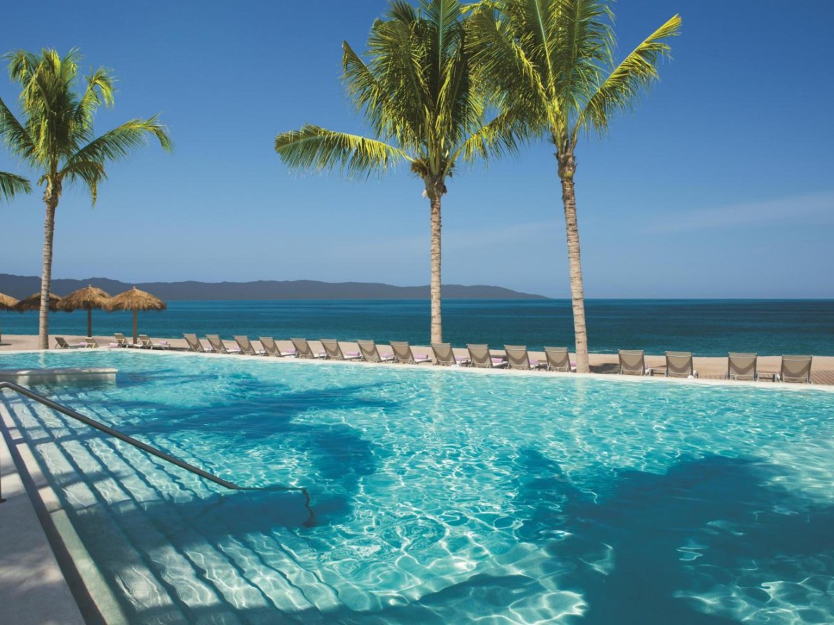 Pool with palm trees and ocean at Secrets Vallarta Bay Resort