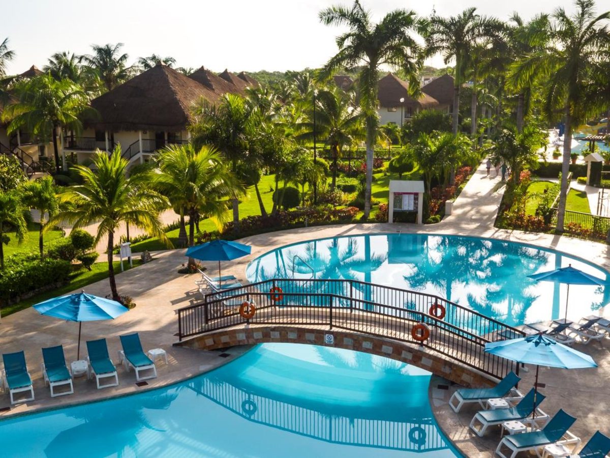 Pool with a footbridge and blue sun loungers among palms at Allegro Cozumel