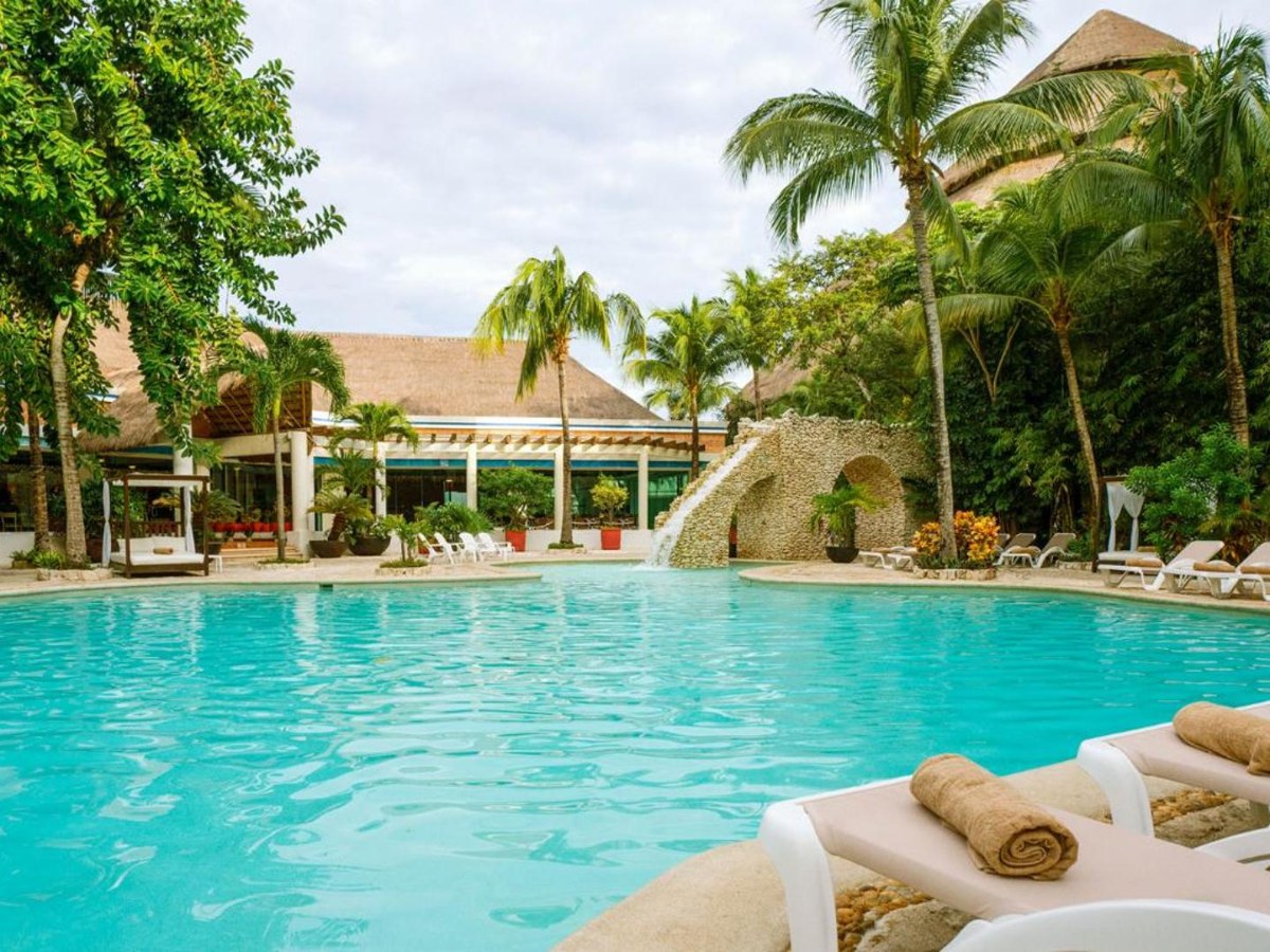 Wide pool with sun loungers and palm trees at Grand Park Royal Cozumel