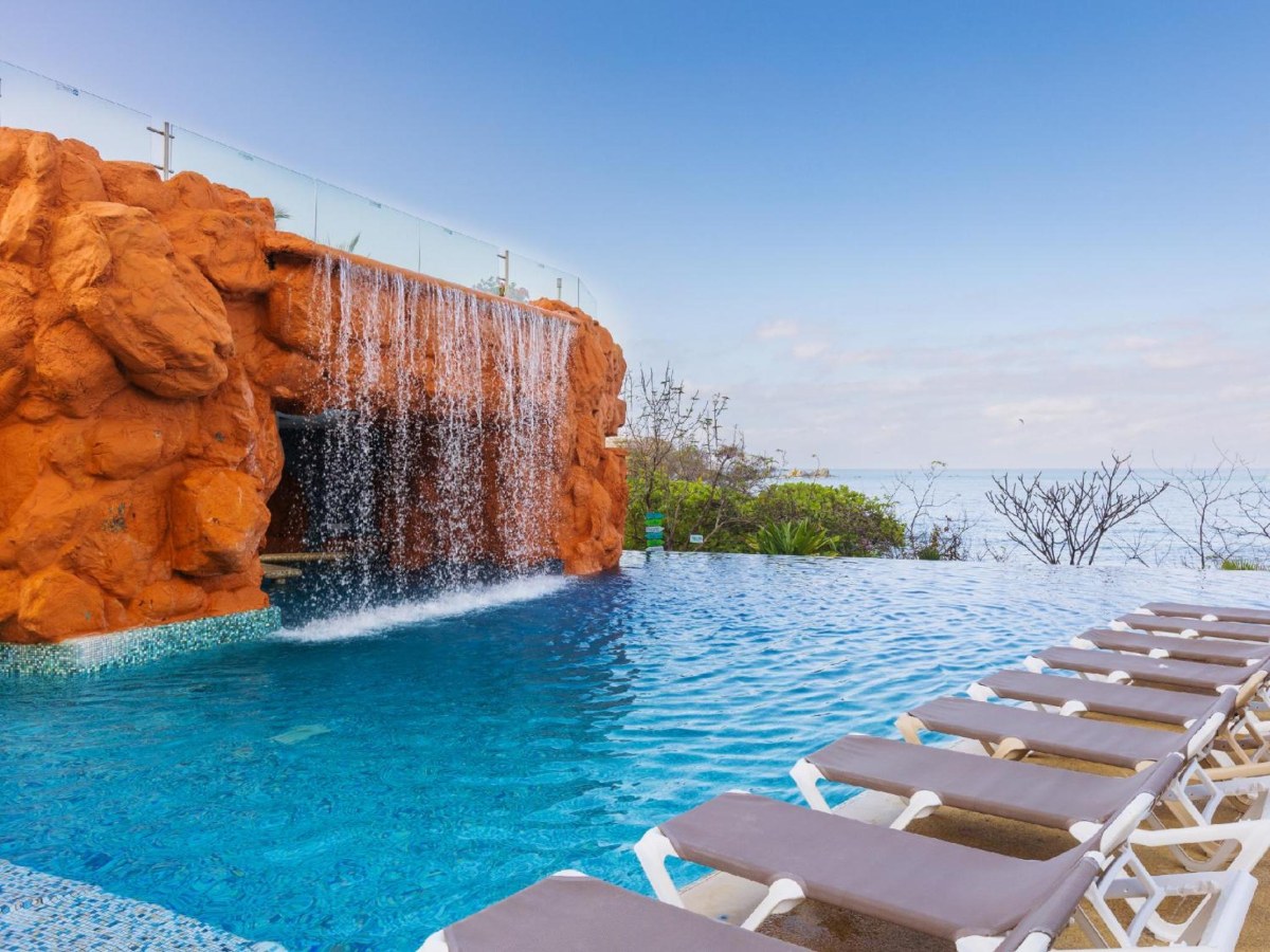 Infinity pool with a waterfall and lounge chairs at Azul Ixtapa Grand All Inclusive Suites