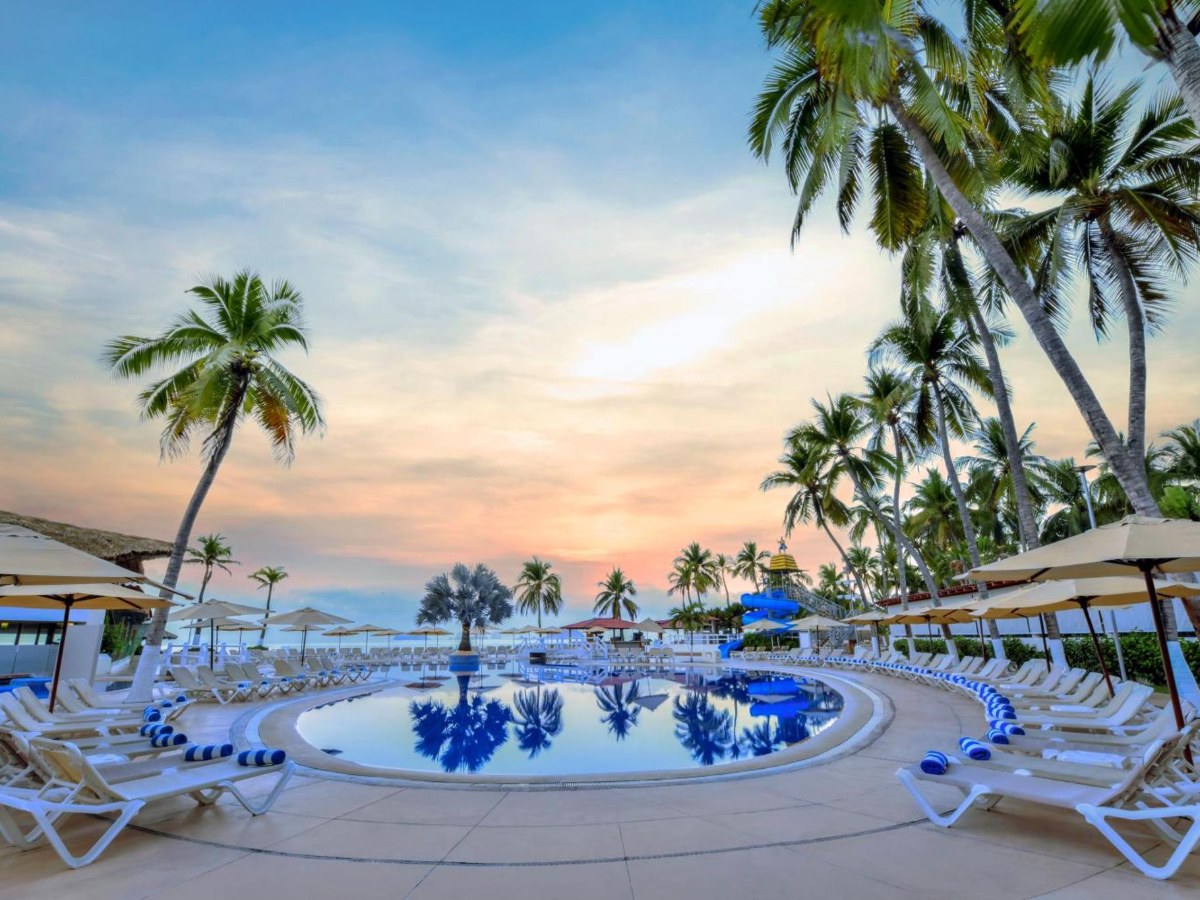 Pool with chairs and palm trees at Krystal Ixtapa All Inclusive