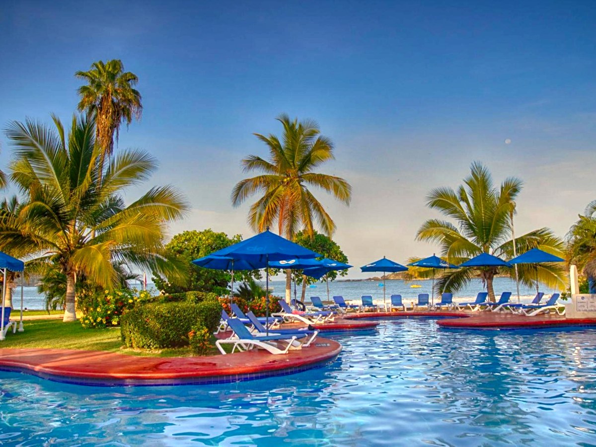 Swimming pool with chairs and umbrellas at Qualton Club Ixtapa All Inclusive
