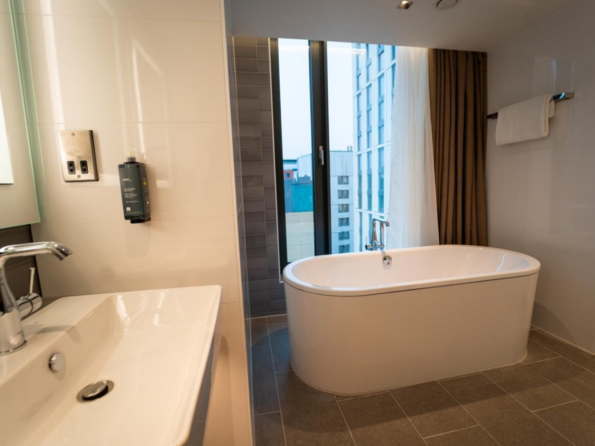 Freestanding bath beside a tall window in the Suite at Clayton Hotel Glasgow City