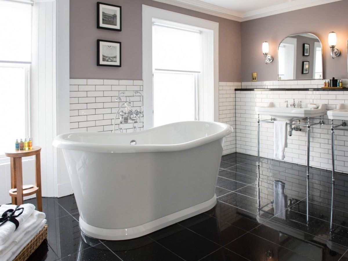 White roll-top bath by a window in the Signature Suite at One Devonshire Gardens
