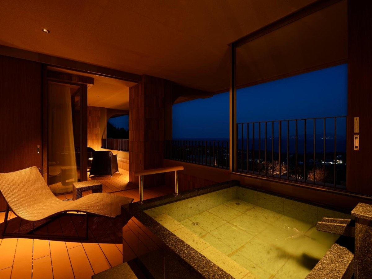 Open-air bath at dusk with a sea view in the Luxury Suite at Kamenoi Hotel Izukogen