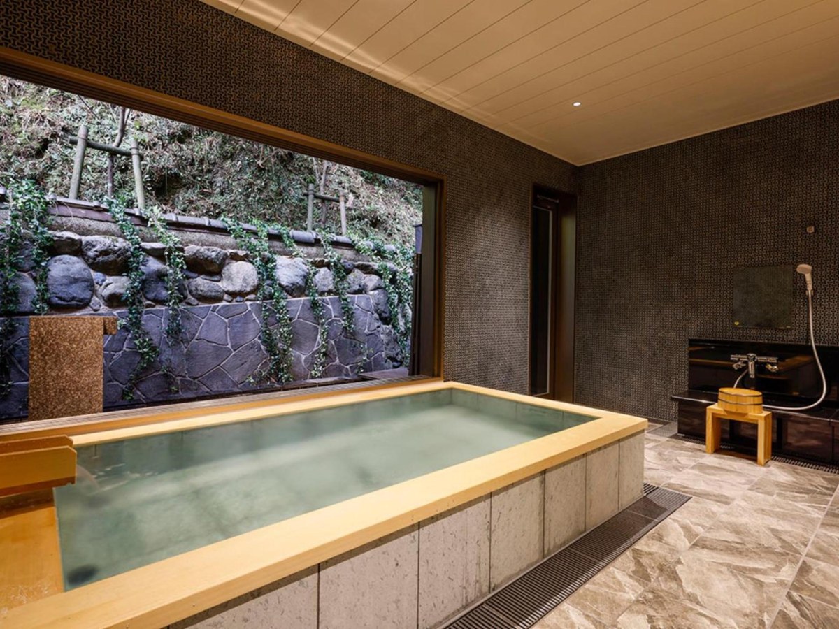 Wood-rimmed bath with a large window at Yuraku Kinosaki Spa & Gardens