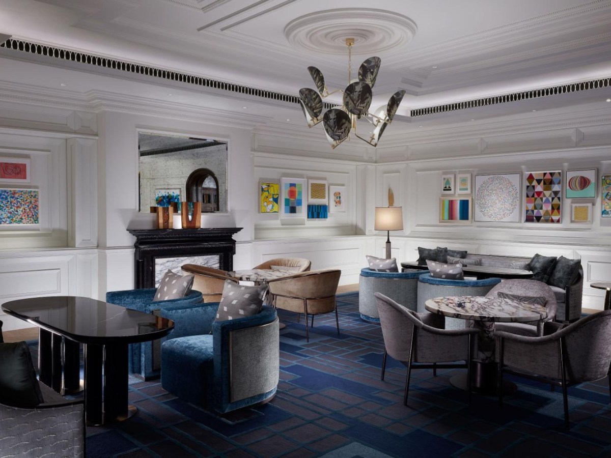 Lobby with a fireplace, tables and chairs at The Londoner Hotel