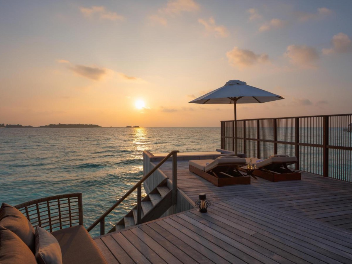 Wooden deck with chairs and an umbrella over the water at a Grand Water Villa with Pool at Conrad Maldives Rangali Island