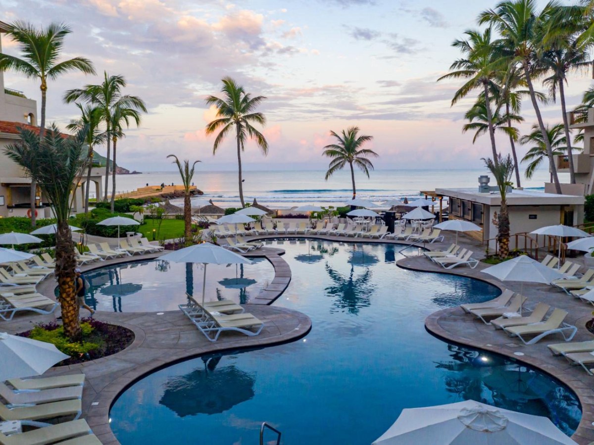 Beachfront pool with palm trees at dusk at Pueblo Bonito Mazatlán