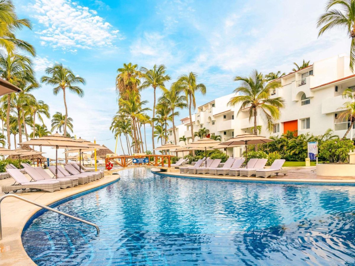 Pool with loungers and palm trees at Marival Emotions