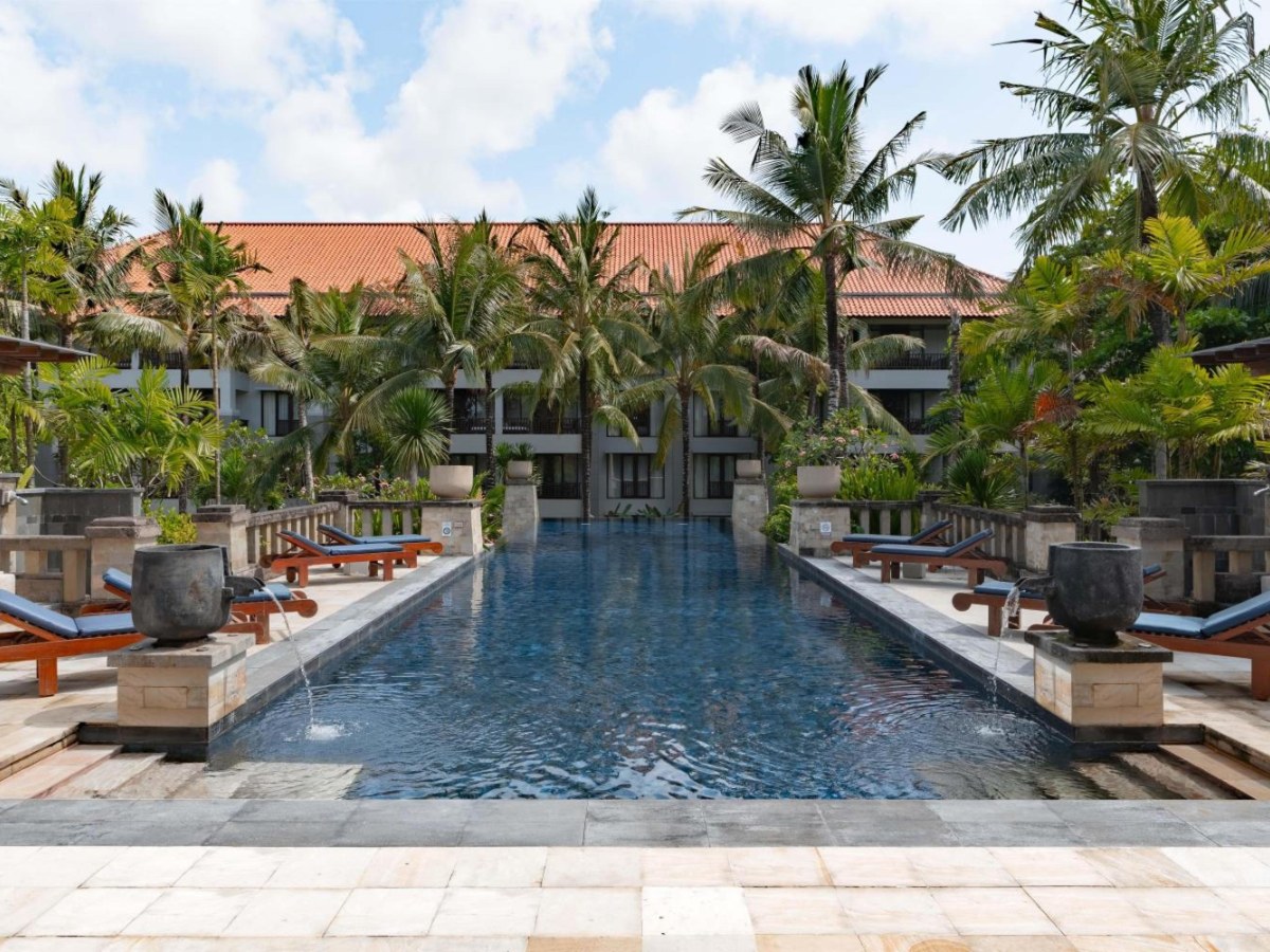 Long lagoon pool between palm trees at Conrad Bali