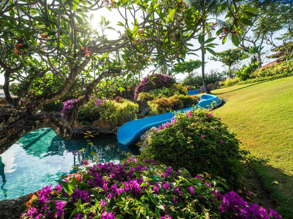 Water slide curving into a pool among flowers at Grand Hyatt Bali