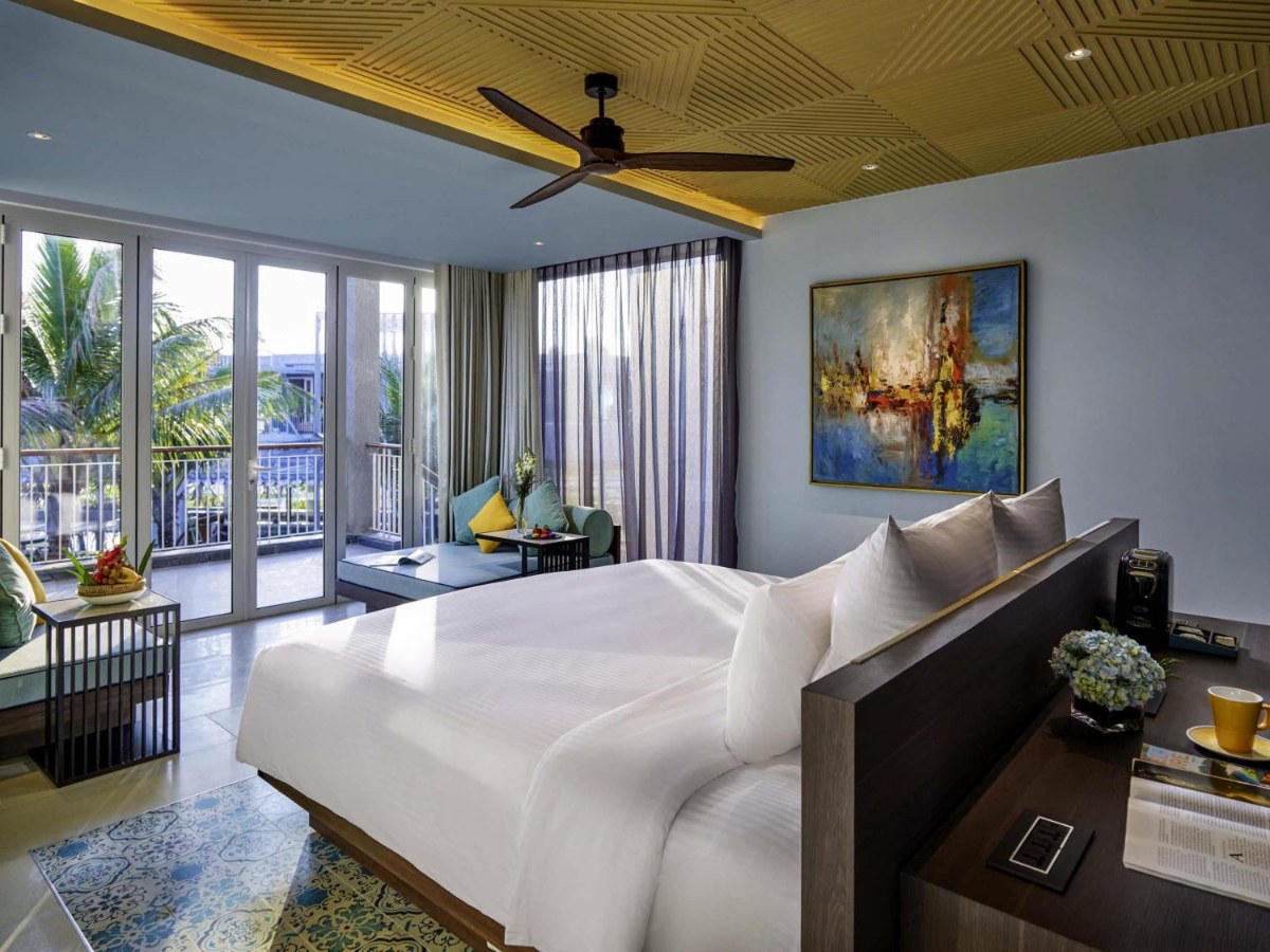 Bedroom with a king bed and living room in a Pullman Phu Quoc family suite