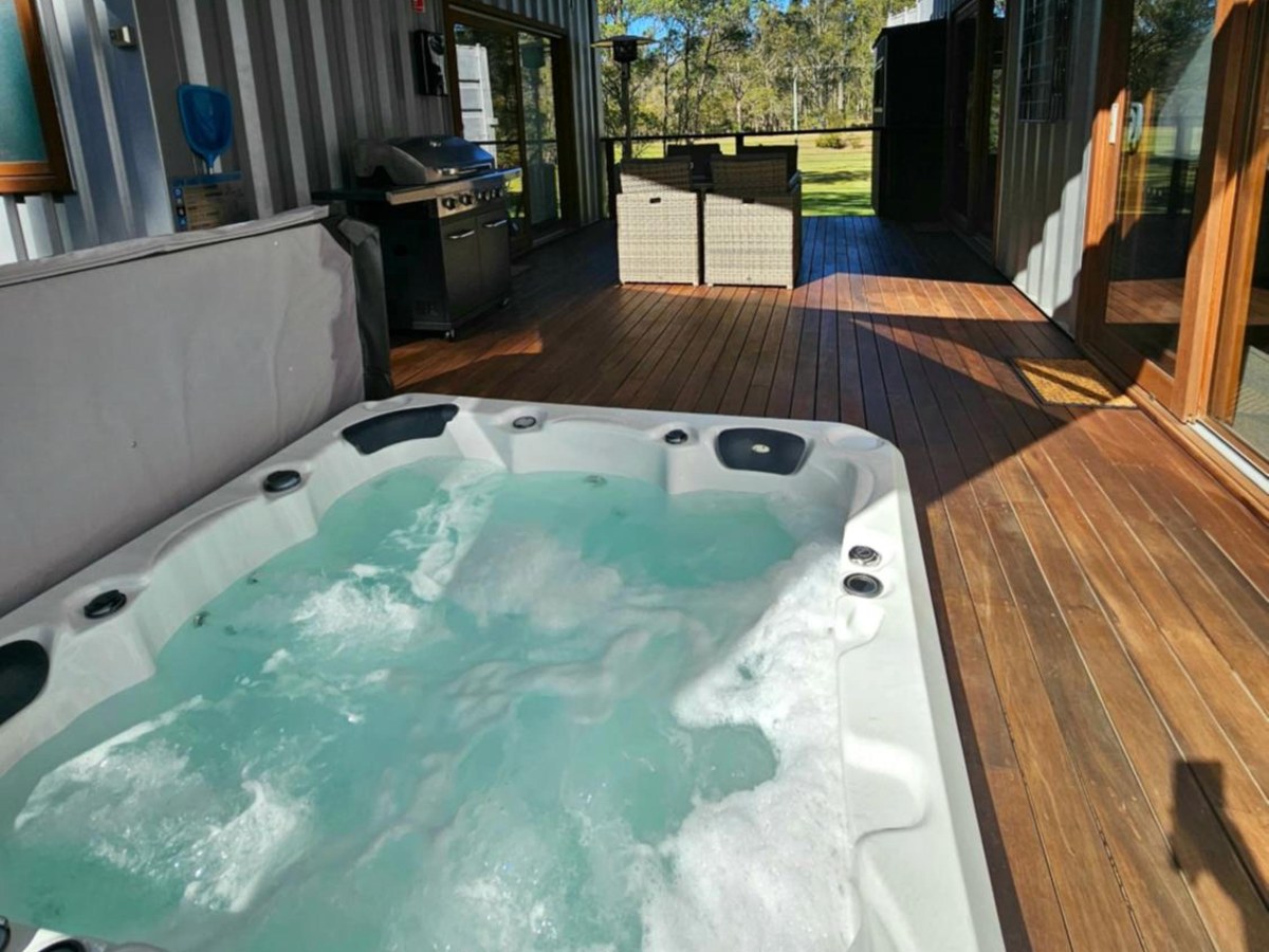 Private hot tub on the covered deck of a container cabin at Tuckers Lane Boutique Accommodation