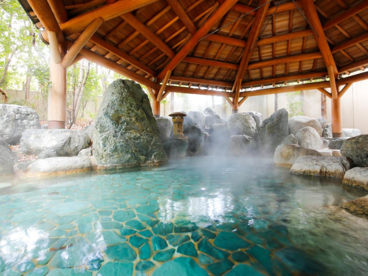 Rock open-air bath under a wooden canopy at Takayama Green Hotel